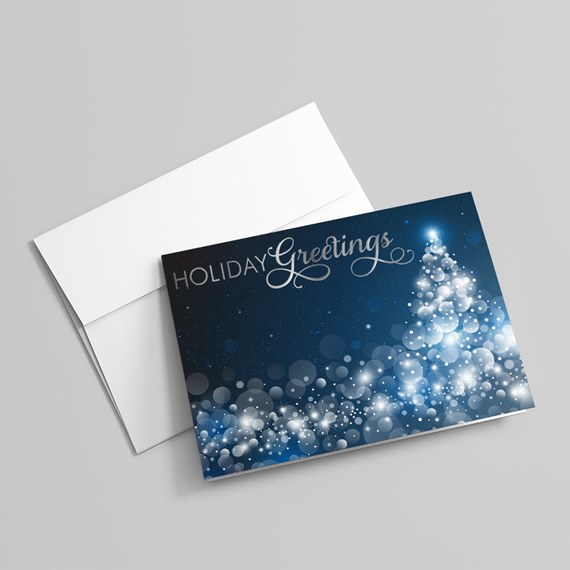 Folded holiday greeting card with navy blue bokeh tree design and white envelope