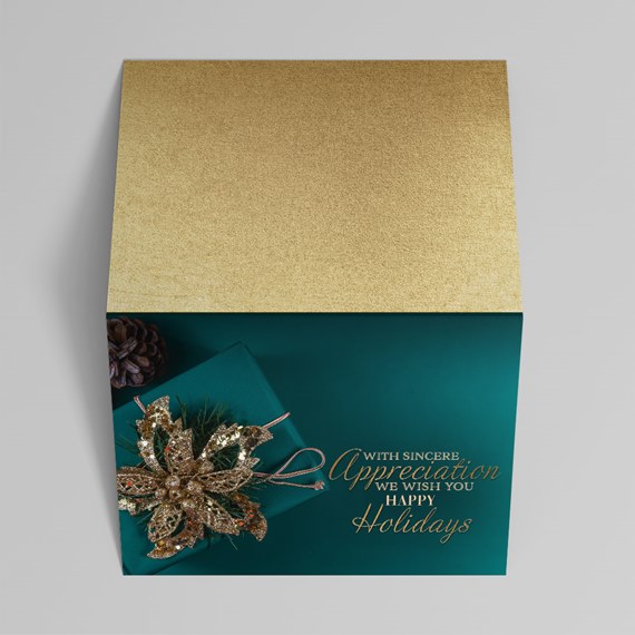 Square holiday gift box with textured gold lid, teal base, glittery gold poinsettia ornament and gold-scripted holiday message