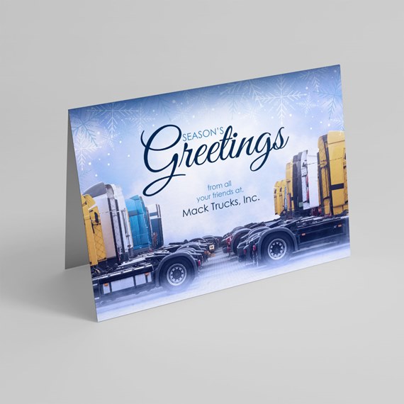 Folded holiday card with 'Season's Greetings' script, snowflake background and a lineup of semi truck cabs