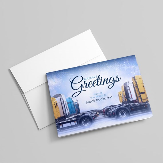 Folded holiday card with "Season's Greetings" text and illustration of a row of semi trucks under a snowflake-patterned blue sky, shown with a white envelope.