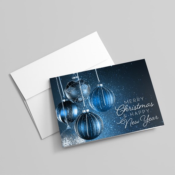 Folded holiday card with hanging blue baubles and 'Merry Christmas & Happy New Year' text on a white envelope