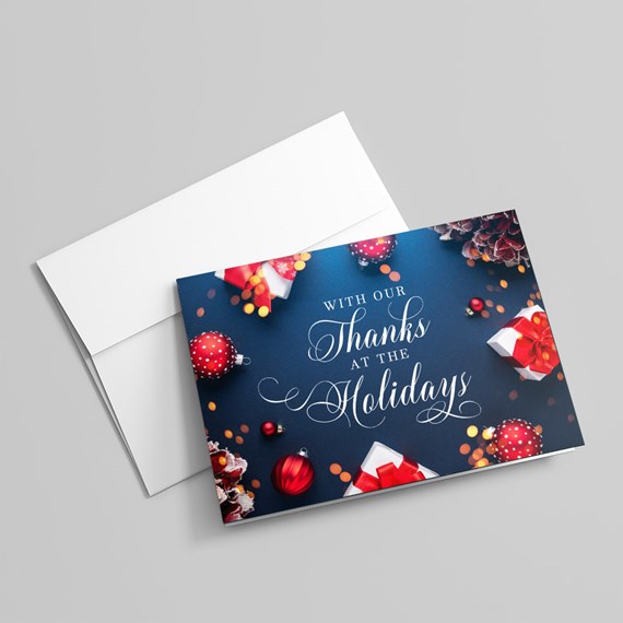Holiday thank-you card with navy front, script typography, red ornaments and gift boxes on a white envelope