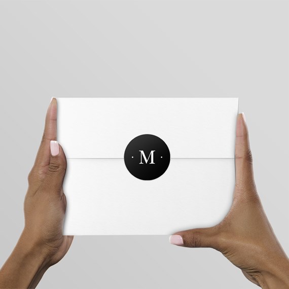 white envelope with black seal and letter M
