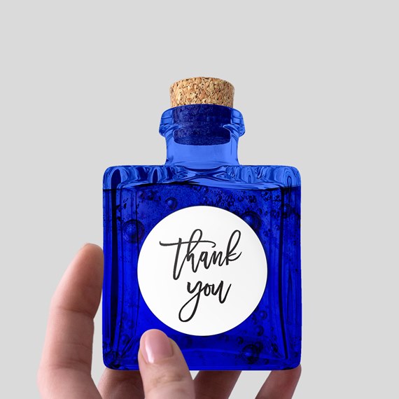 blue glass bottle with cork and thank you label